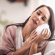 Woman in pink sweater holding an ice pack to the side of her face