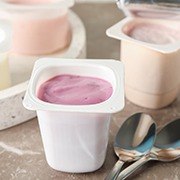 Two spoons next to various yogurt containers on a marble table