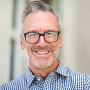 Man with grey hair smiling while wearing glasses