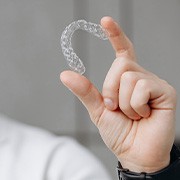 Man holding Invisalign between thumb and forefinger