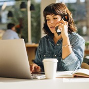 Woman talking on phone and looking at laptop