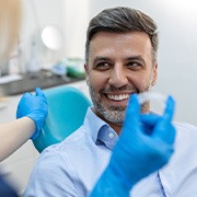 Man smiling at dentist about to hand him Invisalign