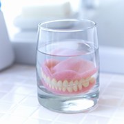 Full dentures in Los Alamitos soaking in glass