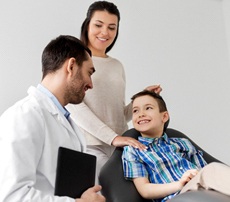 A young boy and his mother talking to a male dentist about his dental care