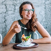 Woman in glasses smiling while eating a healthy snack