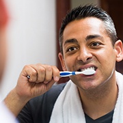 Man brushing his teeth while looking into the mirror