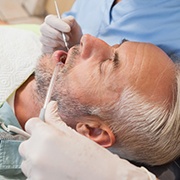 Middle-aged man laying back in dental chair during treatment