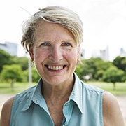 Middle-aged woman smiling while standing outside with trees in background