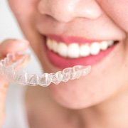 Smiling woman holding clear aligner