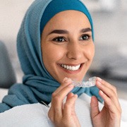 Woman smiling while holding clear aligners