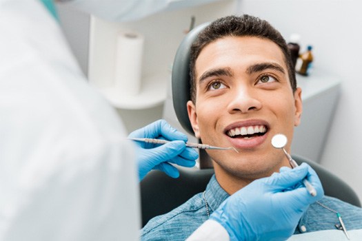 Man in denim shirt in dental chair about to have teeth examined