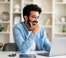 Man in blue shirt smiling while working from home