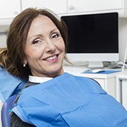 Middle-aged woman in dental chair smiling while looking at camera