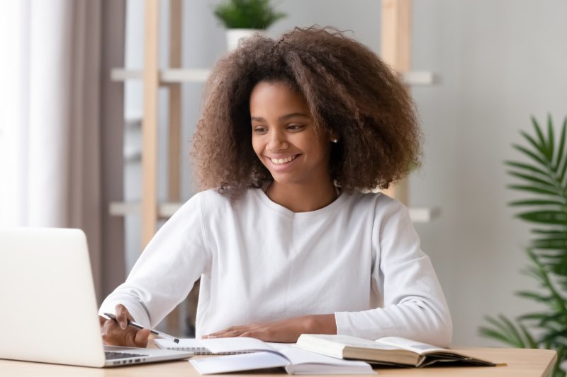 Teen girl smiling while doing homework