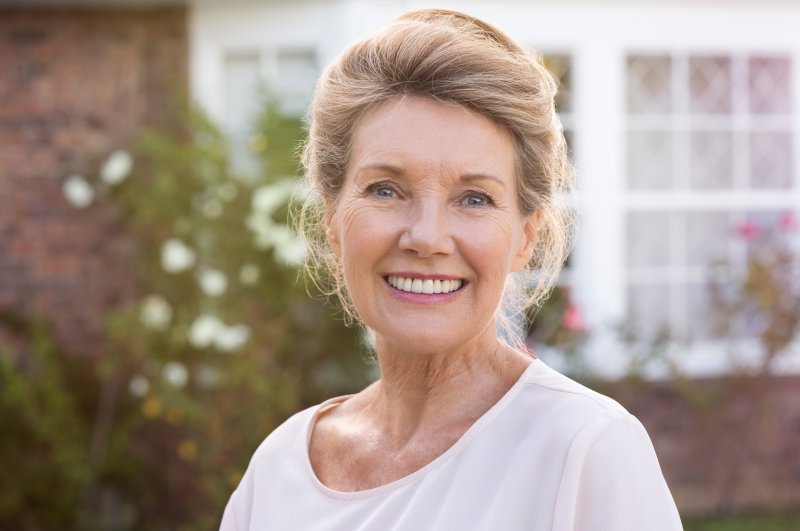 An older woman smiling after receiving dental implants.