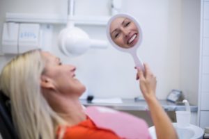mature woman dental chair smile in mirror 