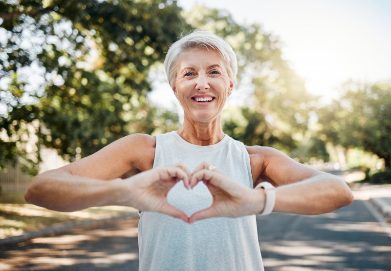 Lady smiles while making shape of heart with her hands