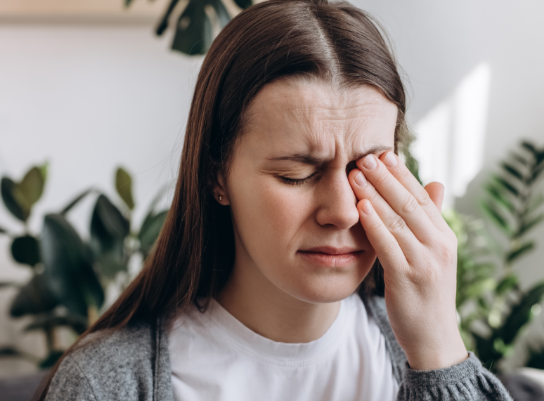 Woman holding hand over eye, grimacing